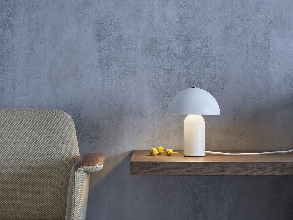 Minimal table lamp placed on a bedside table in a contemporary luxury hotel room creating warm ambient lighting.