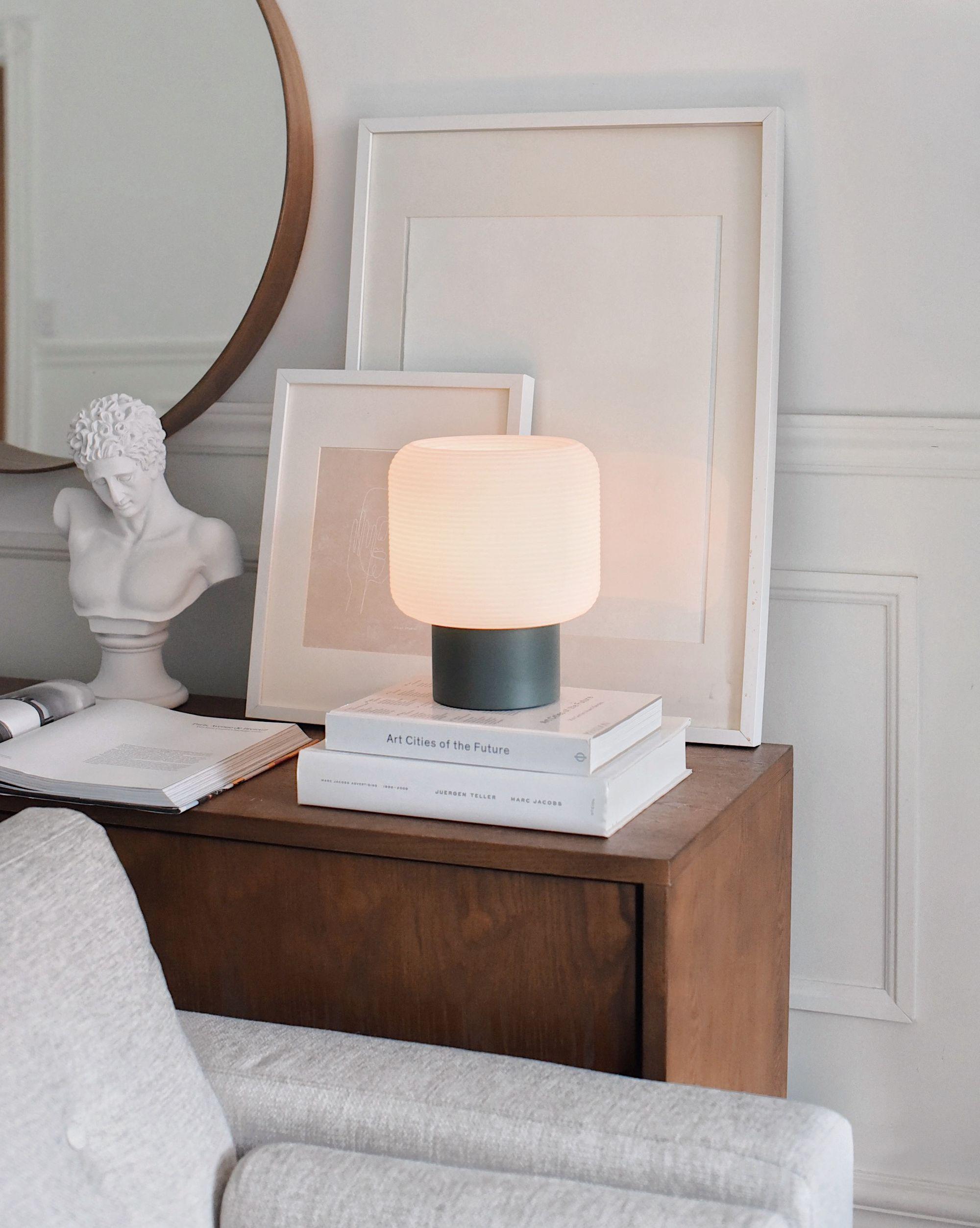 Minimal table lamp placed on a bedside table in a contemporary luxury hotel room creating warm ambient lighting.