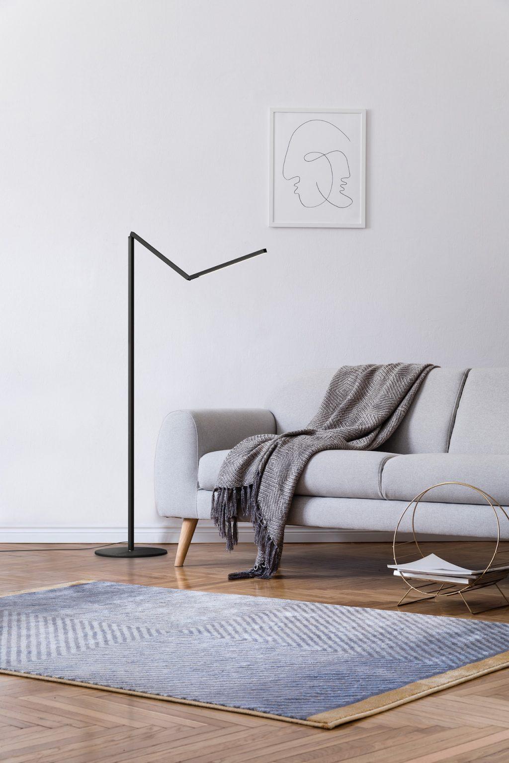Minimal floor lamp positioned beside a contemporary sofa in a luxury residential living room, creating warm ambient illumination.