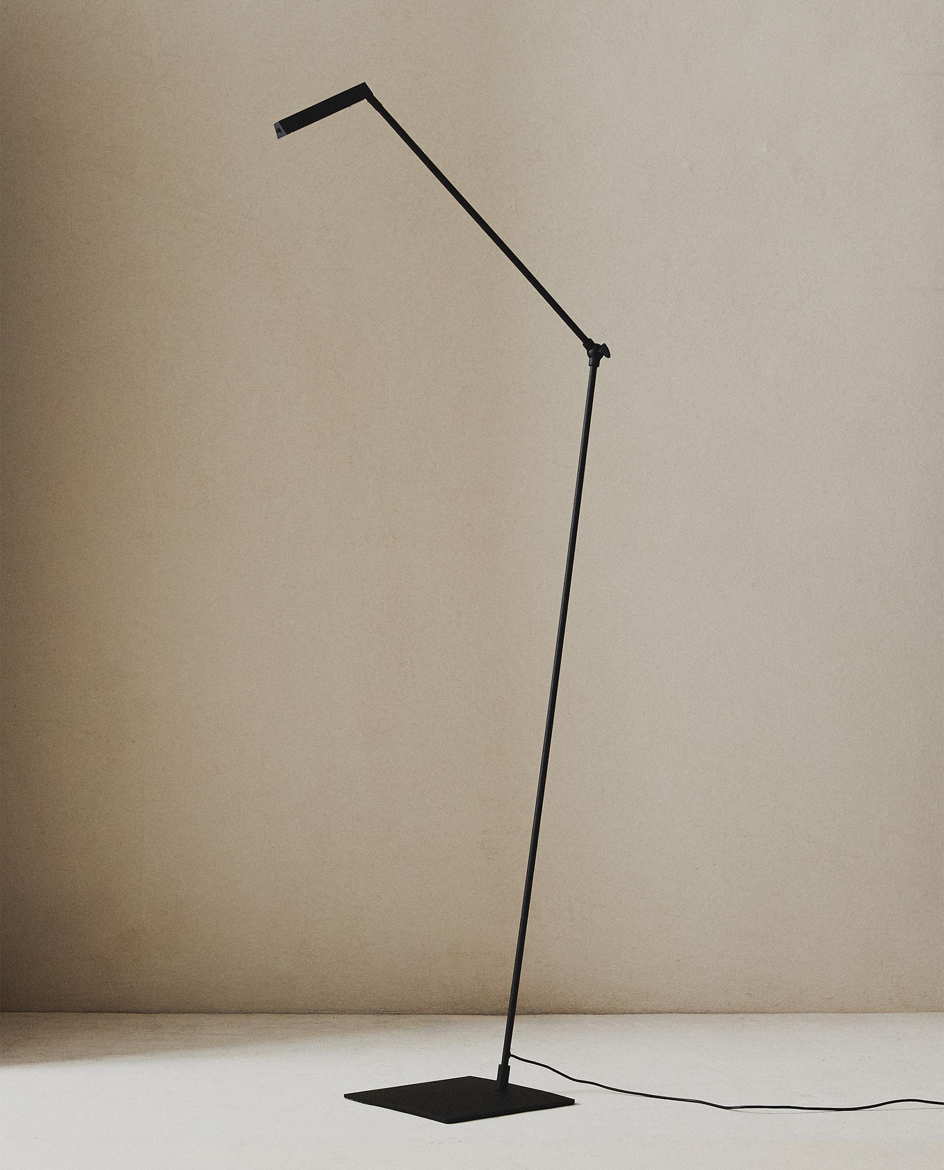 Minimal floor lamp positioned beside a contemporary sofa in a luxury residential living room, creating warm ambient illumination.