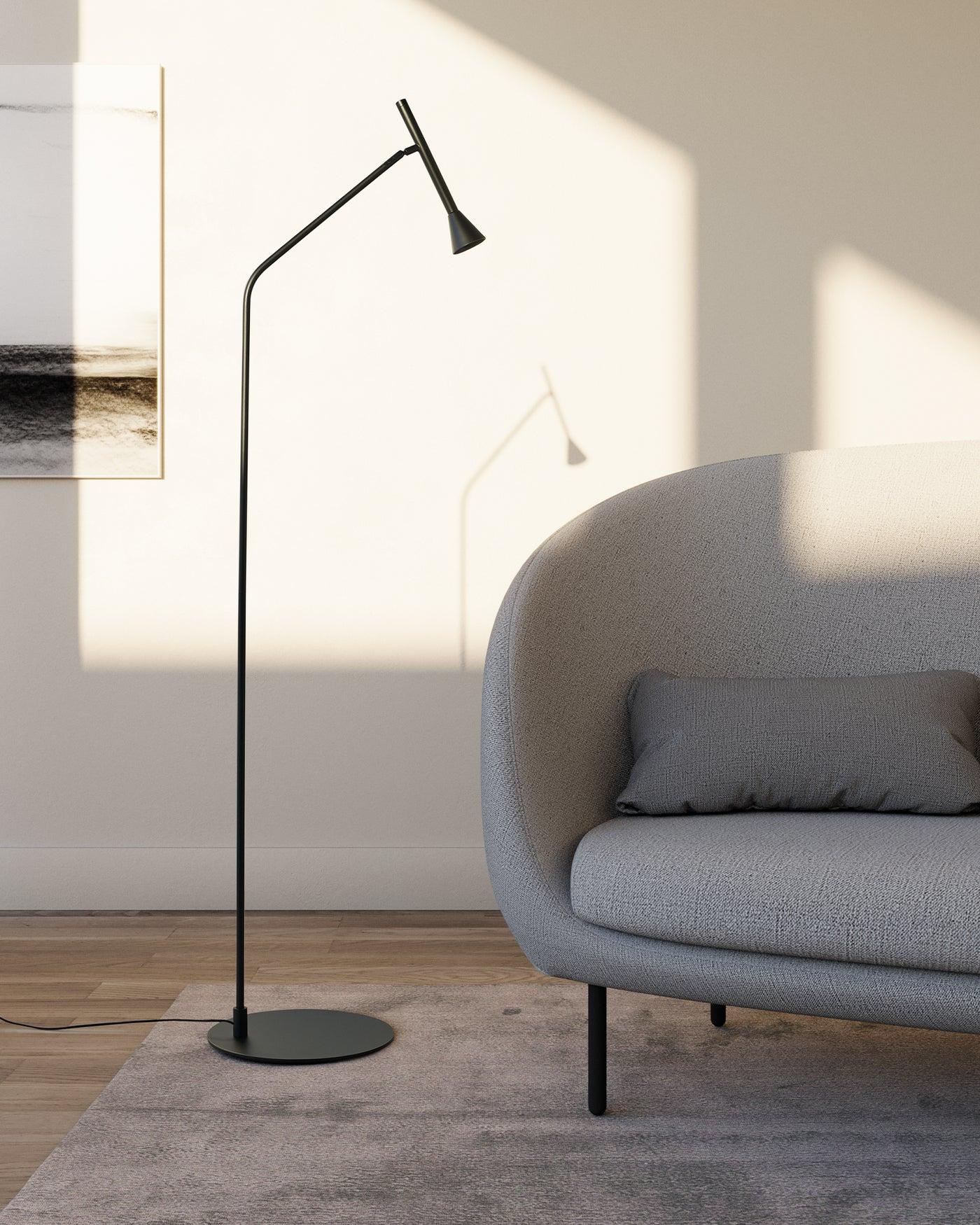 Minimal floor lamp positioned beside a contemporary sofa in a luxury residential living room, creating warm ambient illumination.