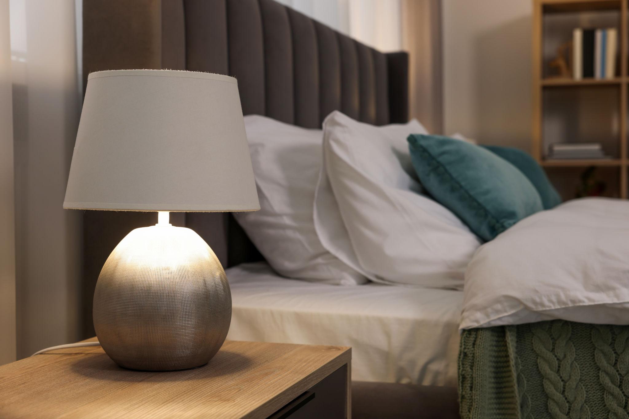 Bedside table lamp placed on a nightstand in a luxury hotel suite creating comfortable ambient lighting for evening use.
