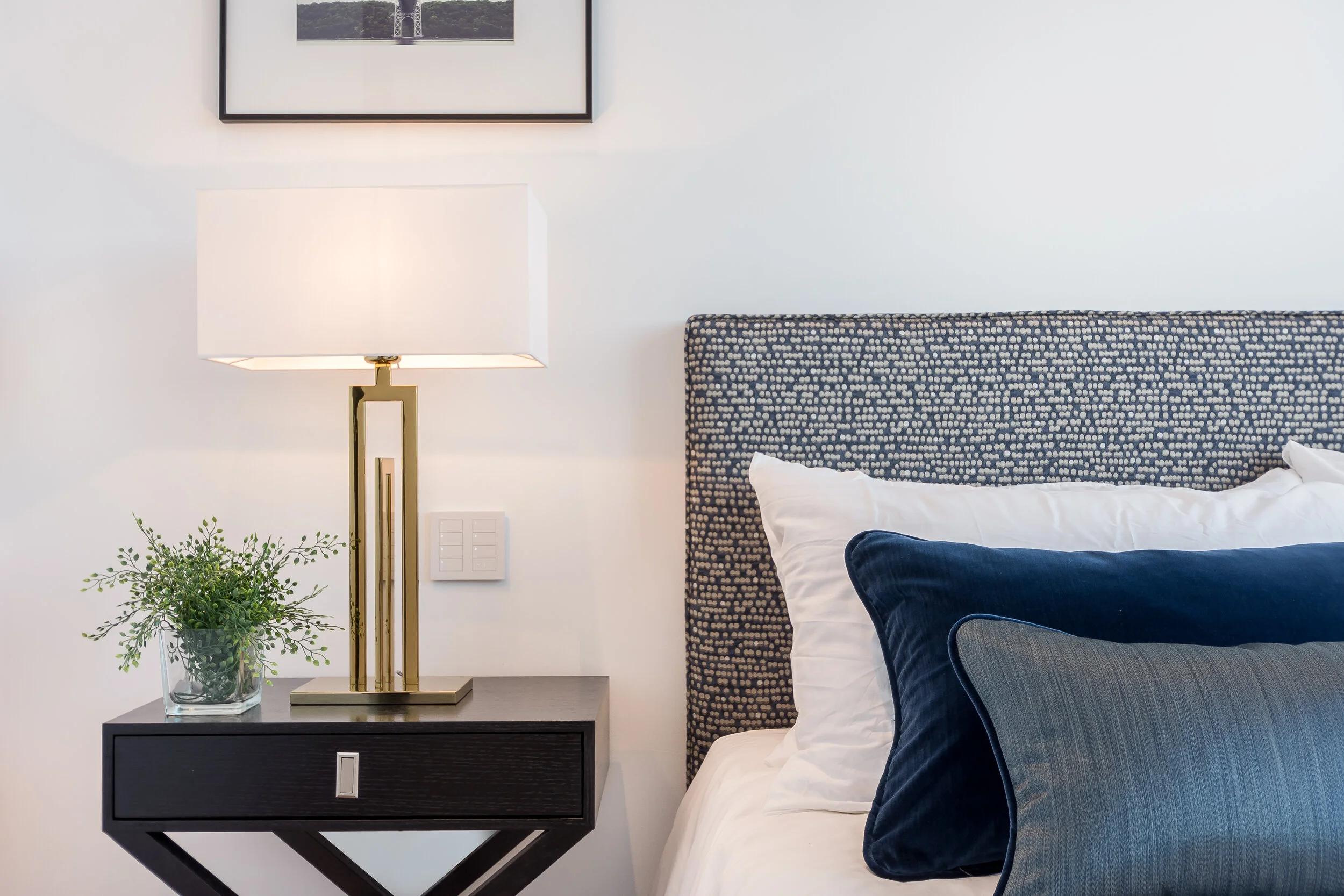 Bedside table lamp placed on a nightstand in a luxury hotel suite creating comfortable ambient lighting for evening use.