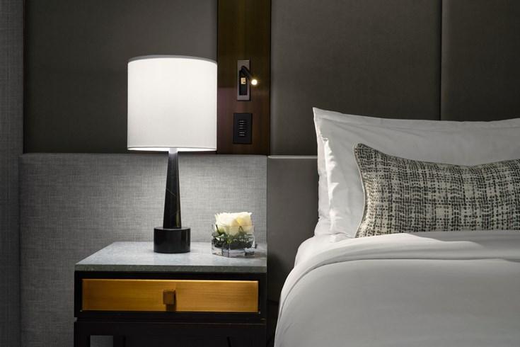 Bedside table lamp placed on a nightstand in a luxury hotel suite creating comfortable ambient lighting for evening use.