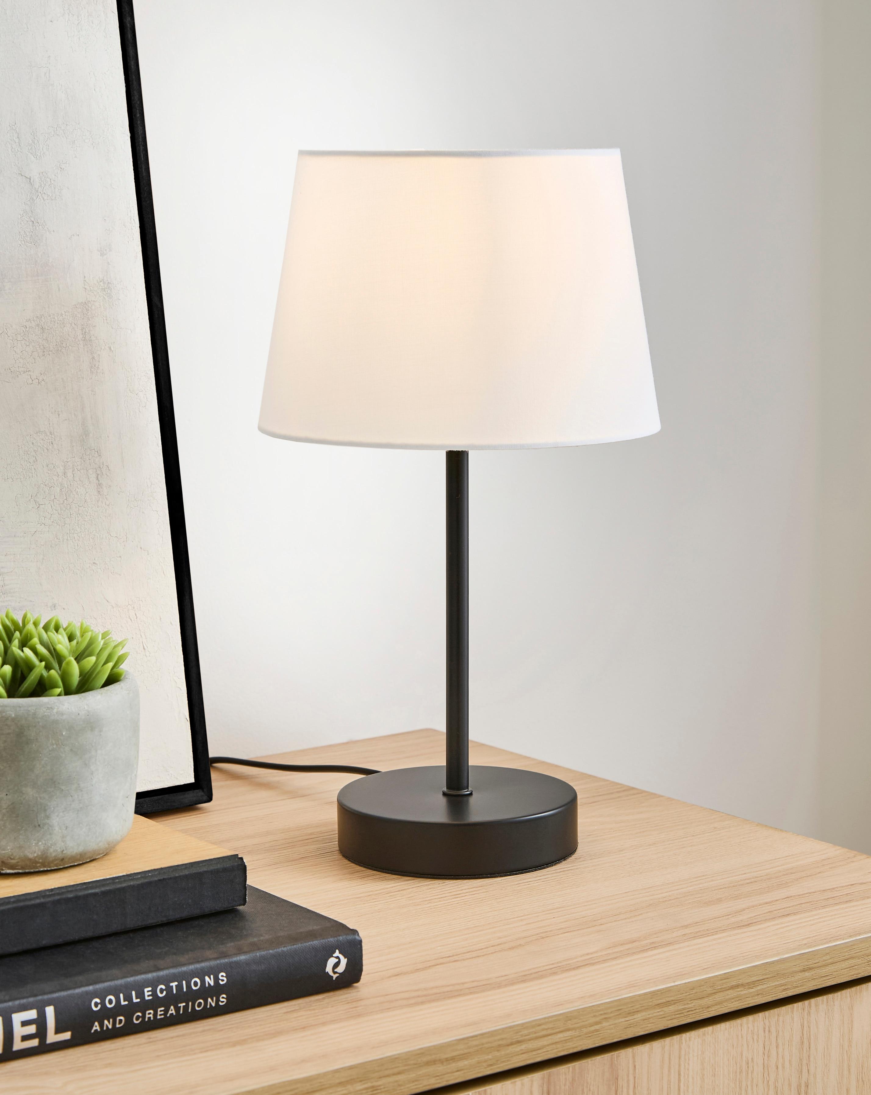 Front view of a bedside table lamp highlighting refined detailing and warm contemporary styling.