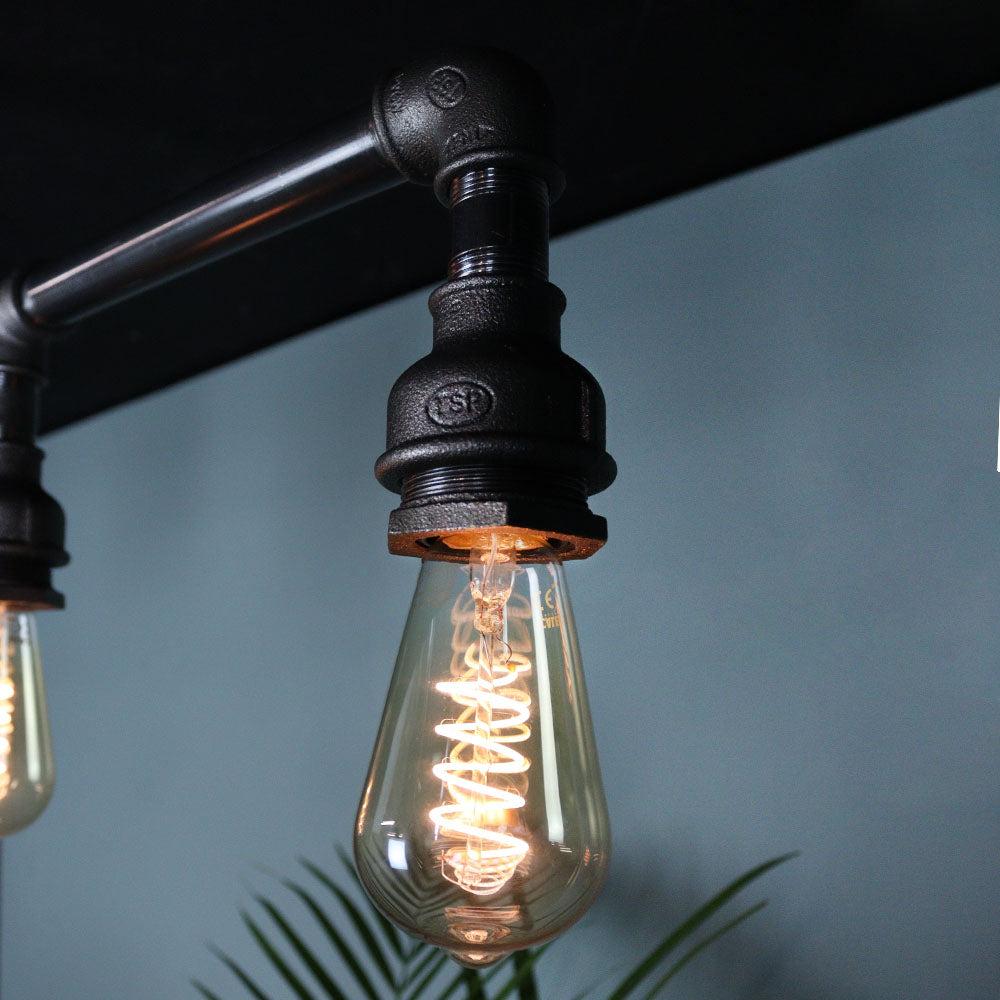 A pipe-based decorative ceiling light combining exposed metal fittings with warm filament bulbs.