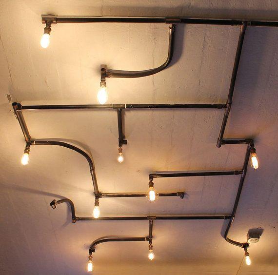 A pipe-based decorative ceiling light combining exposed metal fittings with warm filament bulbs.