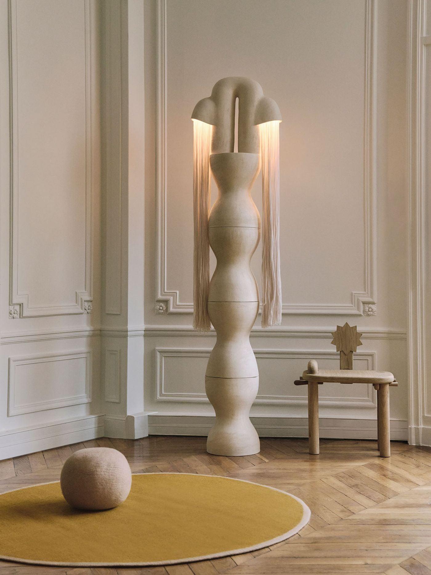 Sculptural floor lamp positioned in a luxury hotel lobby creating a dramatic architectural focal point with warm ambient illumination.