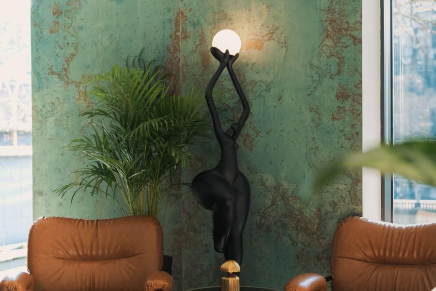 Sculptural floor lamp positioned in a luxury hotel lobby creating a dramatic architectural focal point with warm ambient illumination.