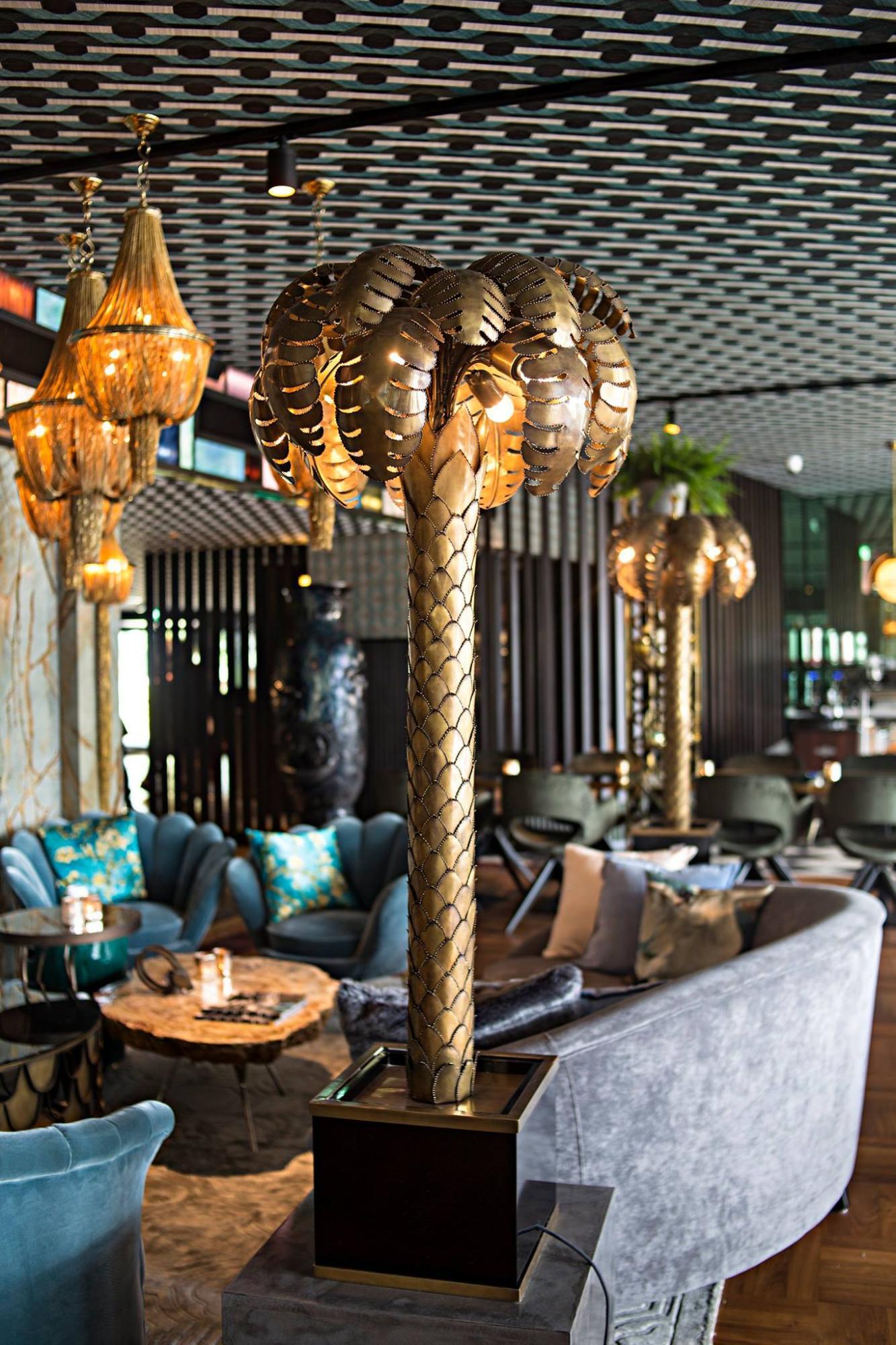 Sculptural floor lamp positioned in a luxury hotel lobby creating a dramatic architectural focal point with warm ambient illumination.
