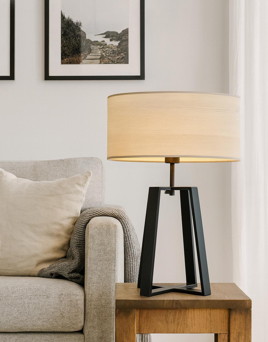 Scandinavian table lamp placed on a wooden side table in a bright contemporary living room, creating warm and comfortable ambient lighting.