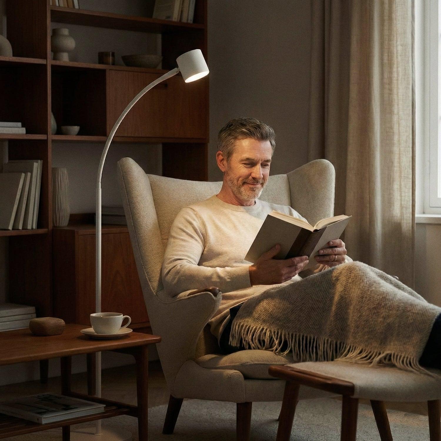 Reading floor lamp positioned beside a lounge chair in a contemporary residential reading corner, providing comfortable focused illumination for extended reading sessions.