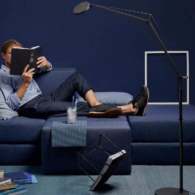 Reading floor lamp positioned beside a lounge chair in a contemporary residential reading corner, providing comfortable focused illumination for extended reading sessions.