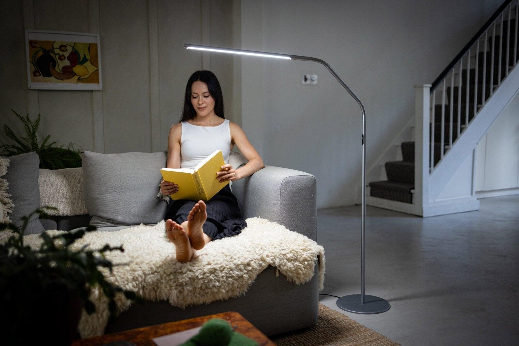 Reading floor lamp positioned beside a lounge chair in a contemporary residential reading corner, providing comfortable focused illumination for extended reading sessions.
