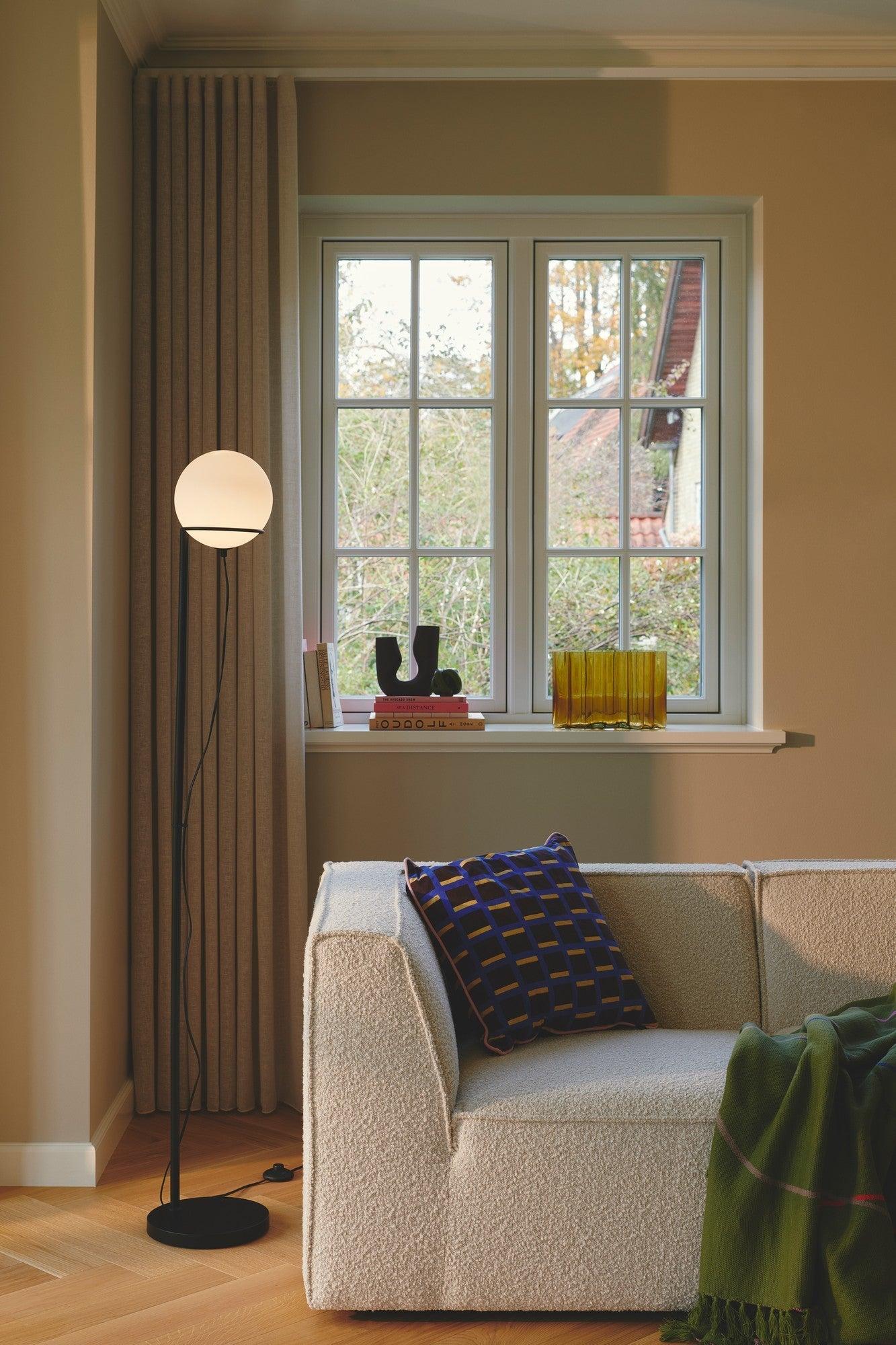 Globe floor lamp positioned beside a seating area in a luxury hotel lounge, creating soft ambient architectural lighting.