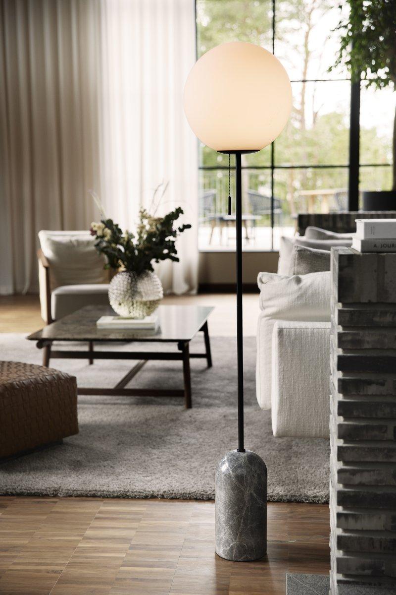 Globe floor lamp positioned beside a seating area in a luxury hotel lounge, creating soft ambient architectural lighting.