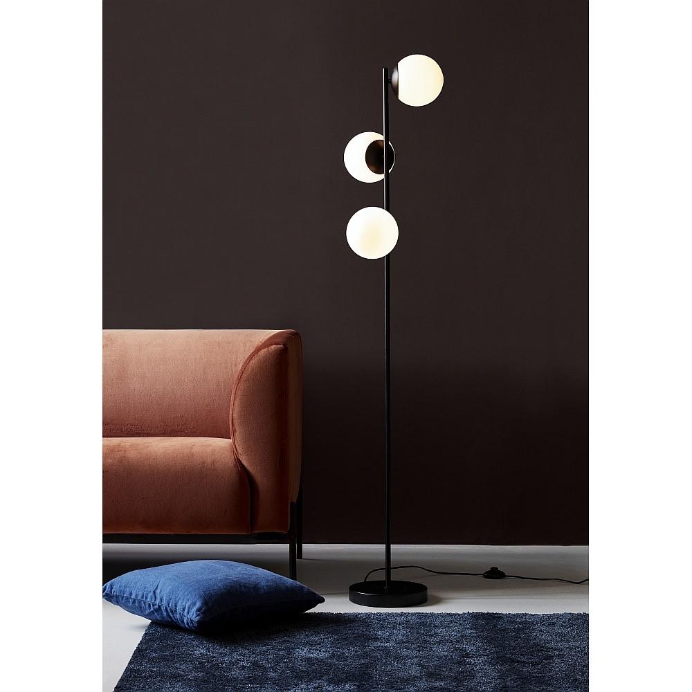 Globe floor lamp positioned beside a seating area in a luxury hotel lounge, creating soft ambient architectural lighting.
