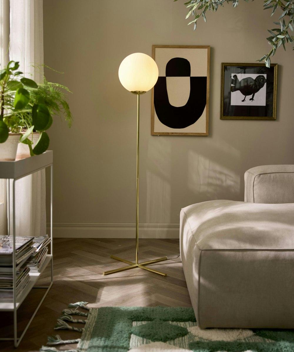 Globe floor lamp positioned beside a seating area in a luxury hotel lounge, creating soft ambient architectural lighting.