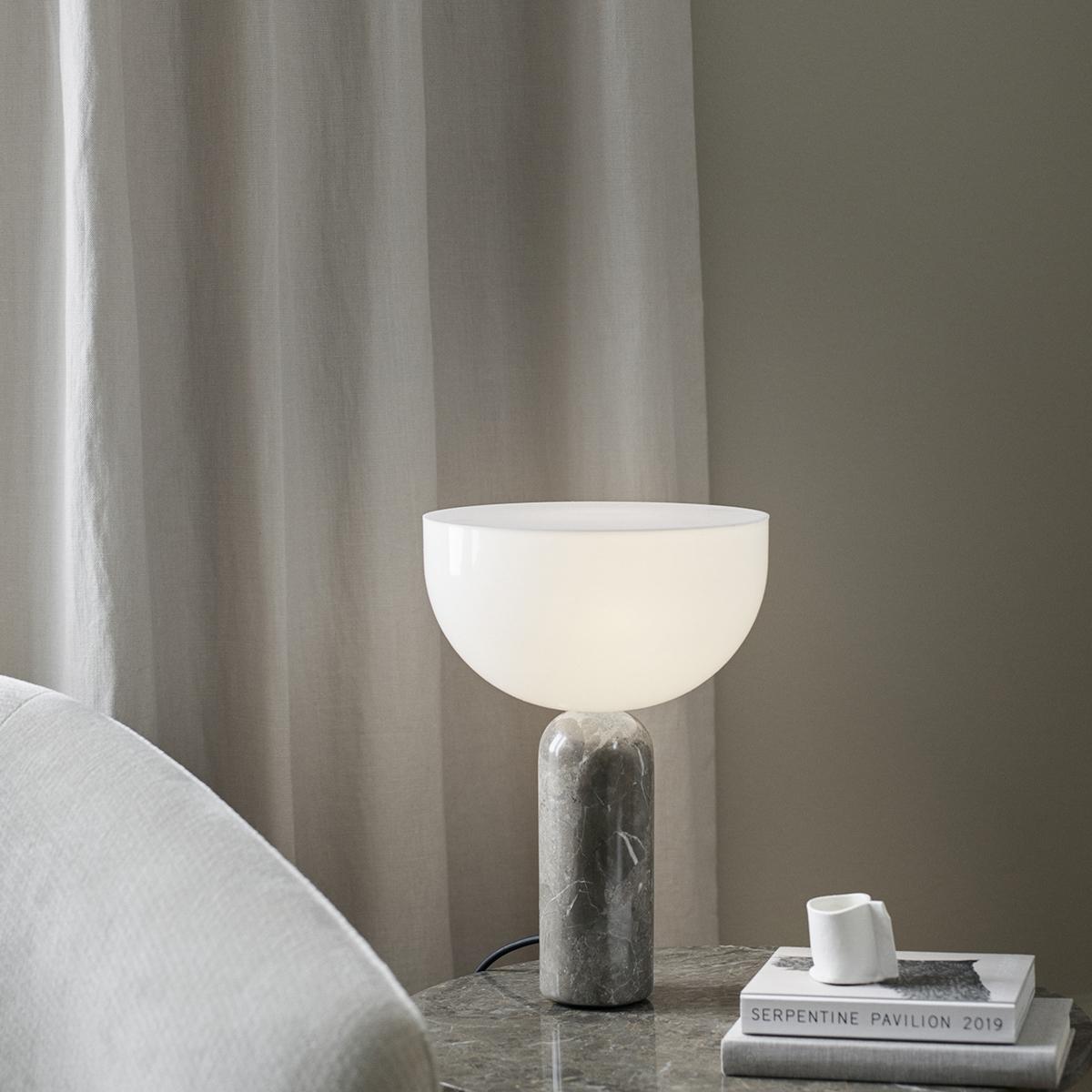 Marble table lamp placed on a bedside table in a luxury hotel suite creating warm ambient lighting and refined architectural elegance.