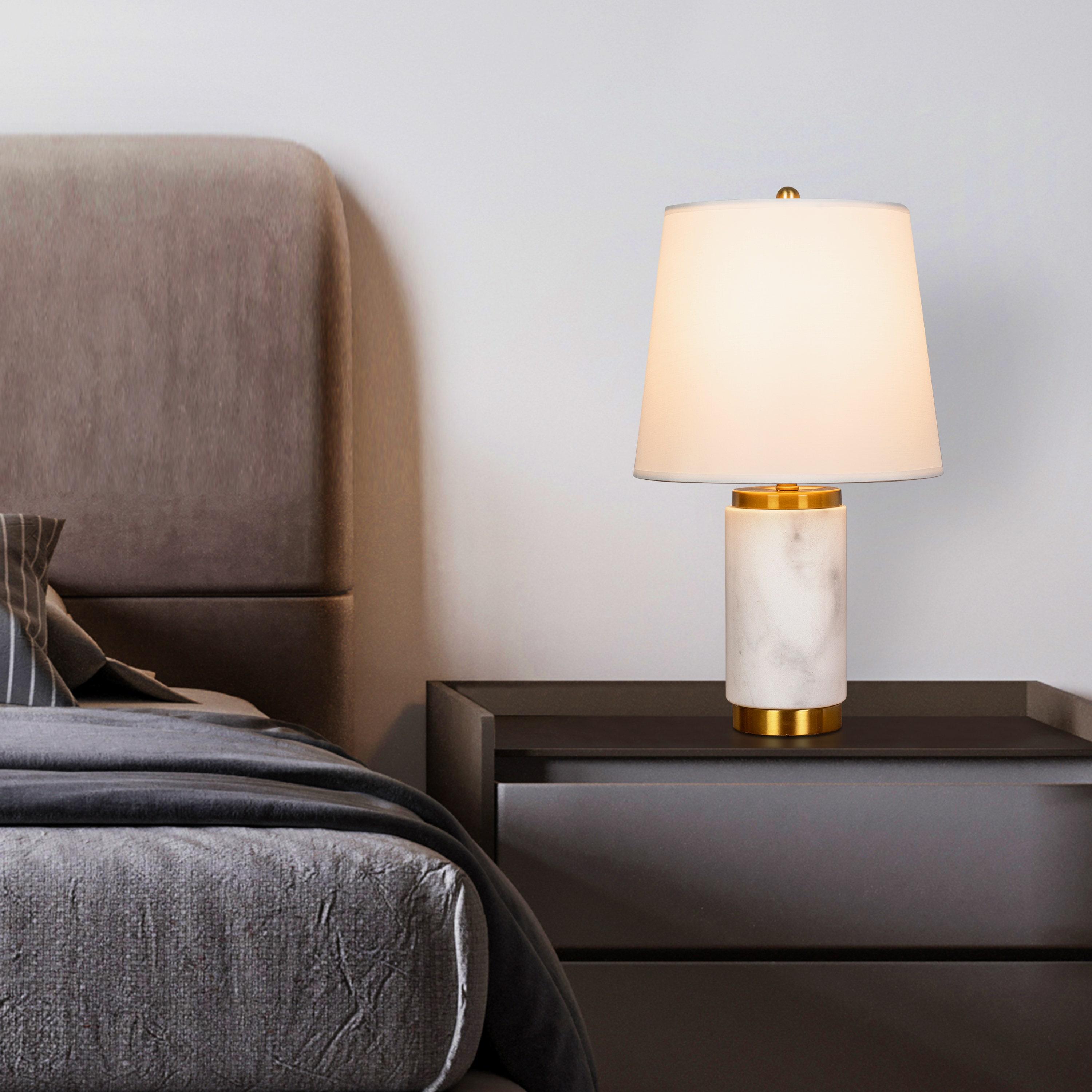 Marble table lamp placed on a bedside table in a luxury hotel suite creating warm ambient lighting and refined architectural elegance.