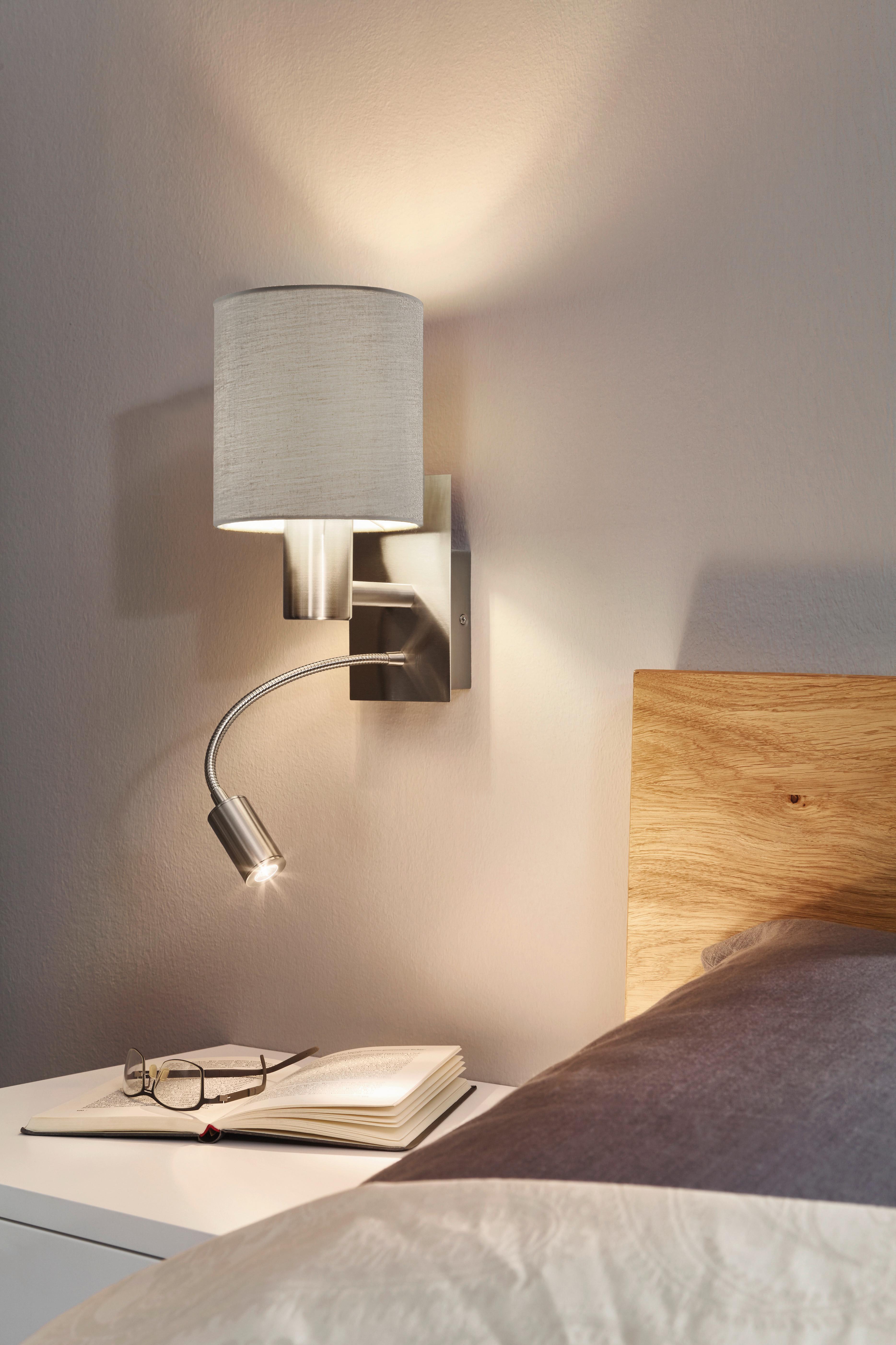 Bedside wall lamp installed beside a luxury hotel bed providing warm ambient illumination.