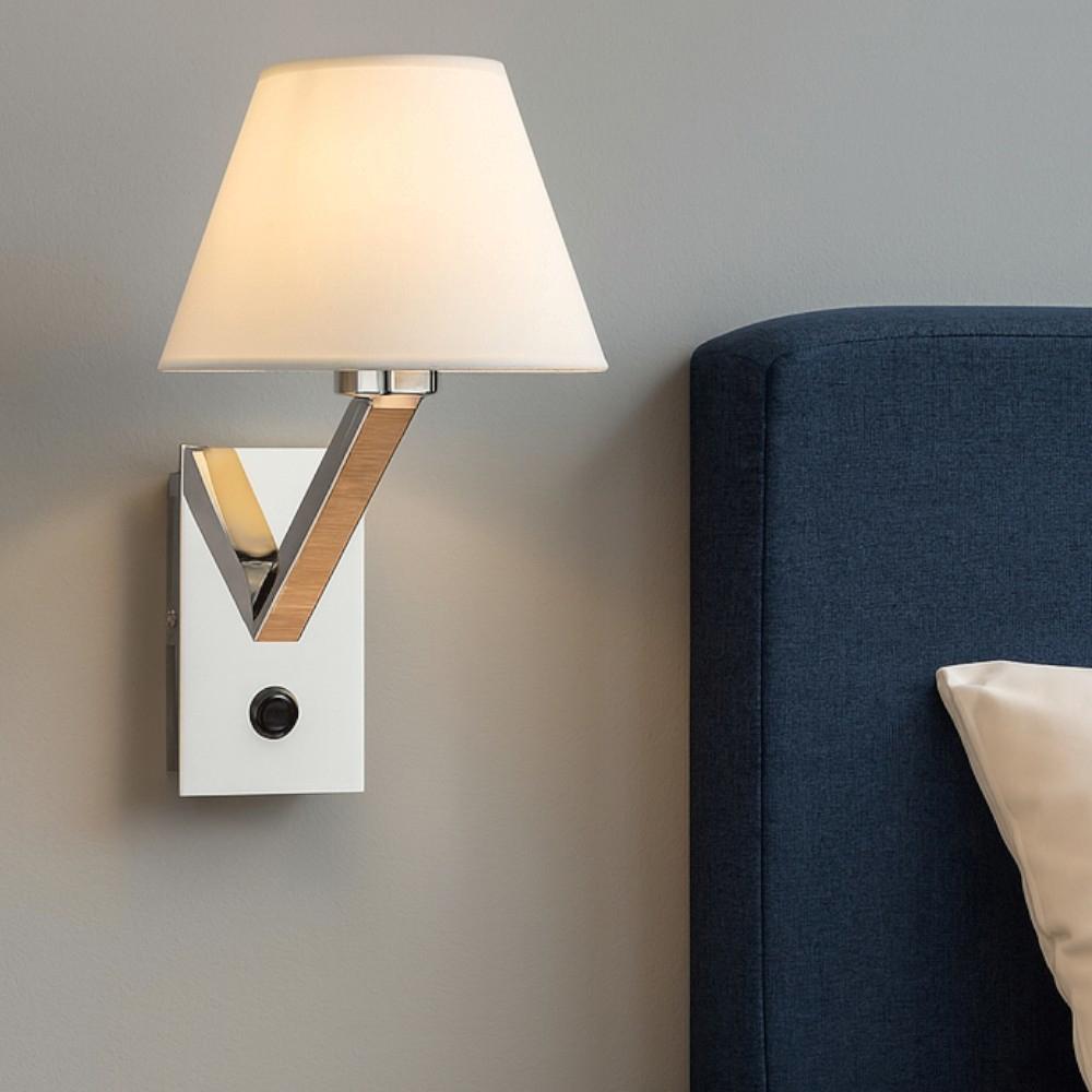Bedside wall lamp installed beside a luxury hotel bed providing warm ambient illumination.