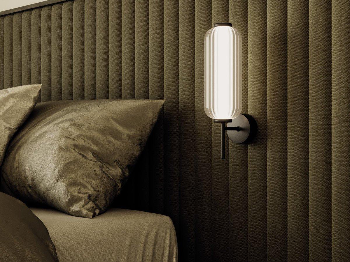 Bedside wall lamp installed beside a luxury hotel bed providing warm ambient illumination.