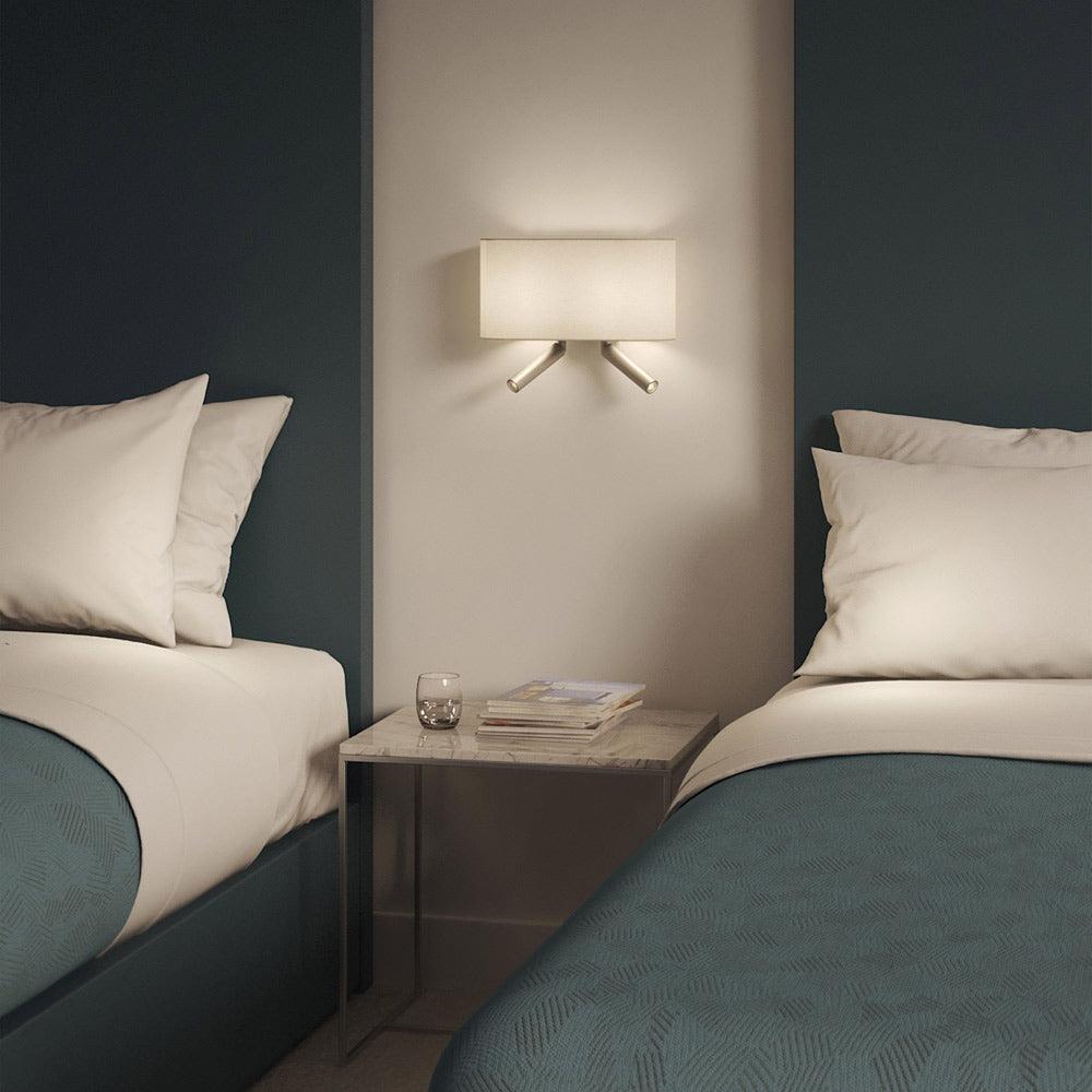 Bedside wall lamp installed beside a luxury hotel bed providing warm ambient illumination.
