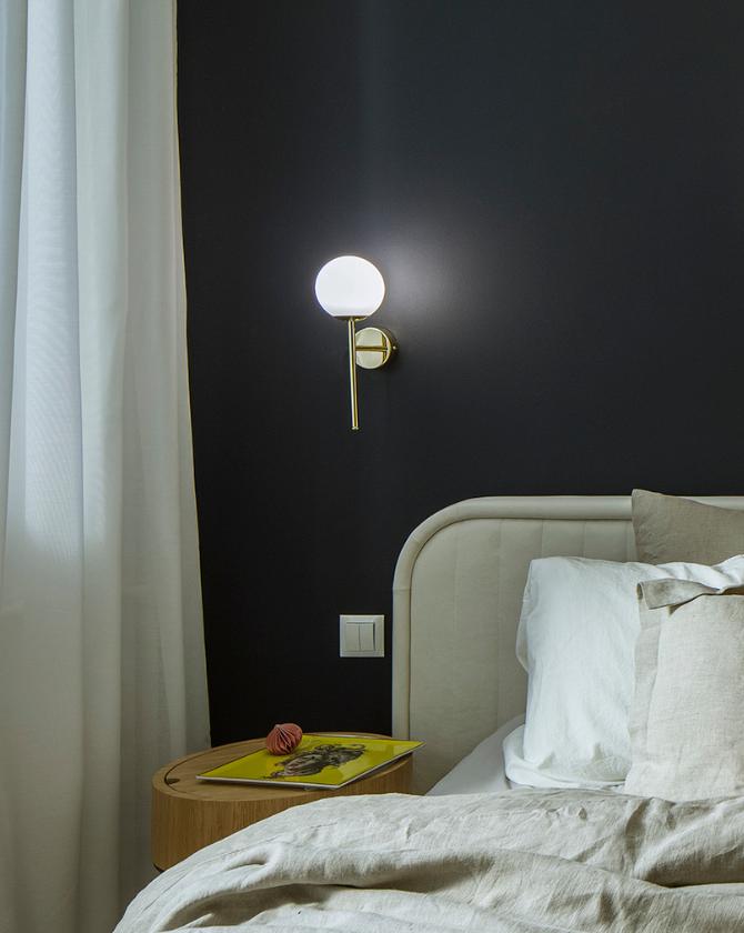 Bedside wall lamp installed beside a luxury hotel bed providing warm ambient illumination.