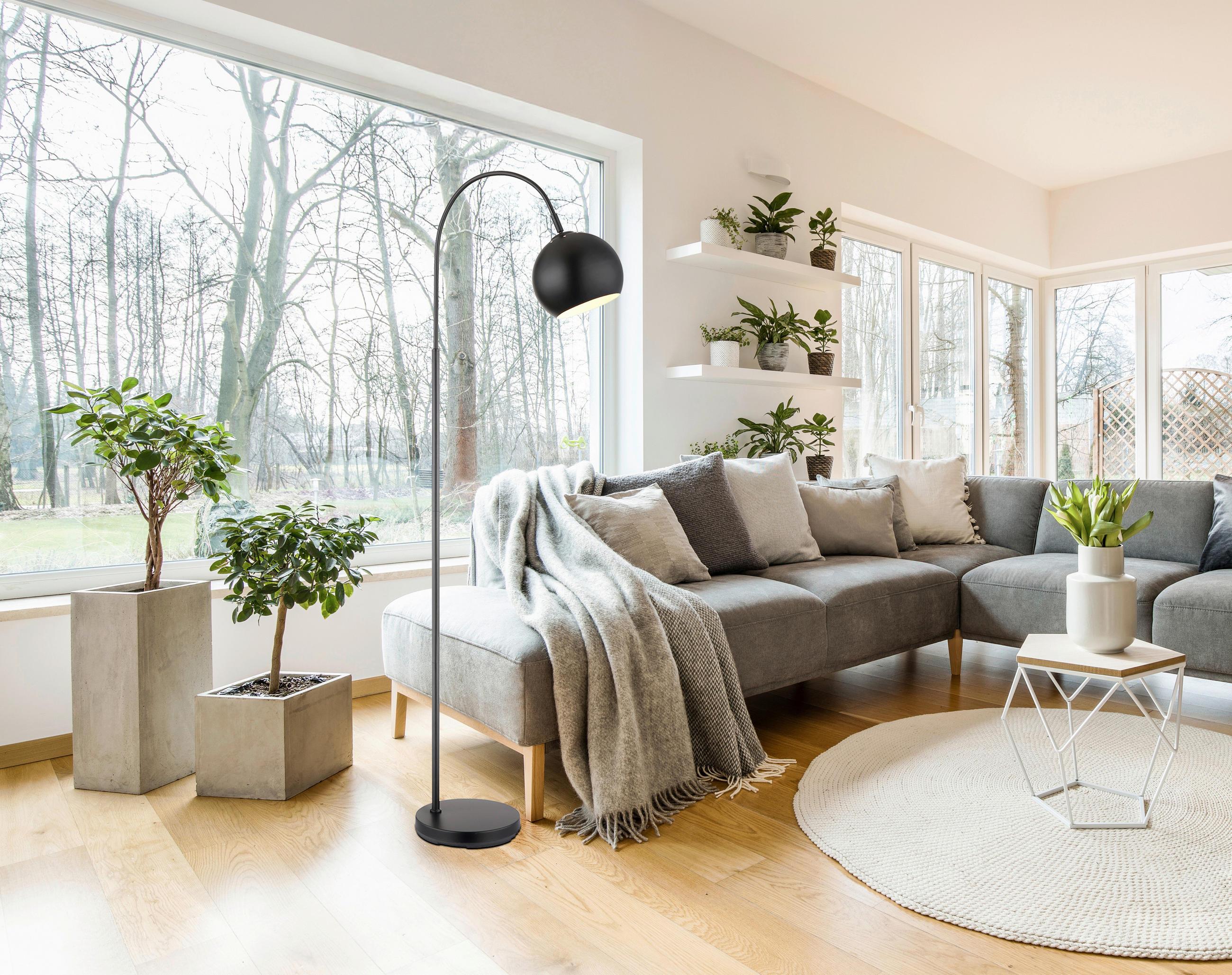 Scandinavian floor lamp positioned beside a lounge chair in a bright contemporary living room, creating warm and comfortable ambient lighting.
