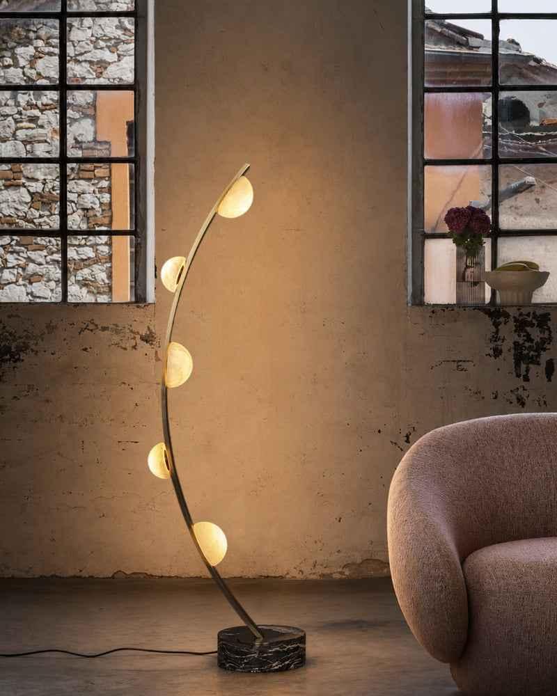Marble floor lamp positioned beside a seating area in a luxury hotel lounge creating warm ambient lighting and timeless architectural elegance.