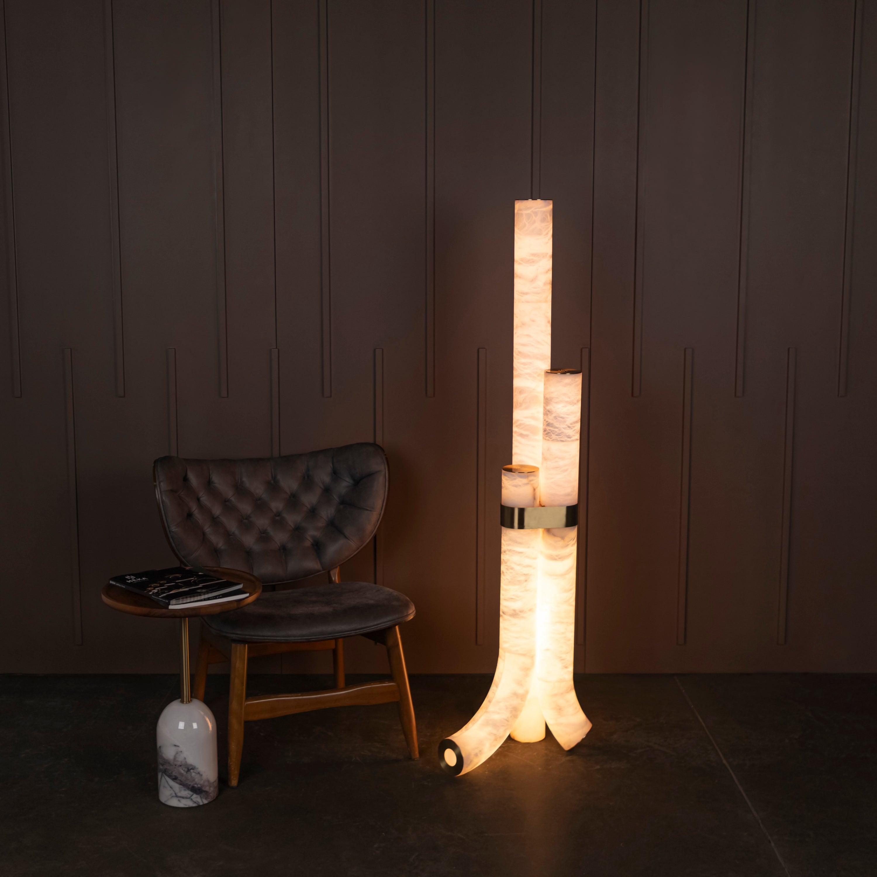 Marble floor lamp positioned beside a seating area in a luxury hotel lounge creating warm ambient lighting and timeless architectural elegance.