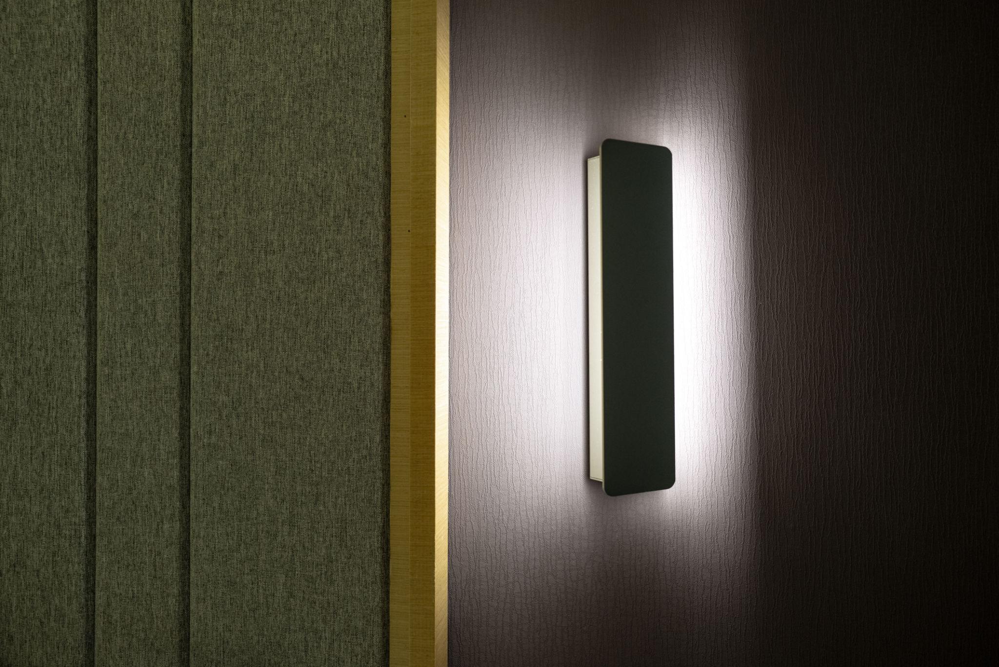 Minimal wall lamp installed in a contemporary hospitality interior.