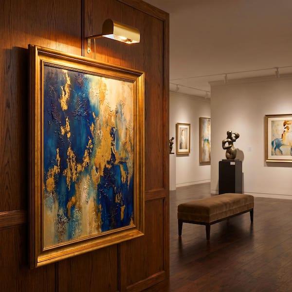 Picture wall lamp illuminating artwork inside a luxury gallery and hospitality interior.