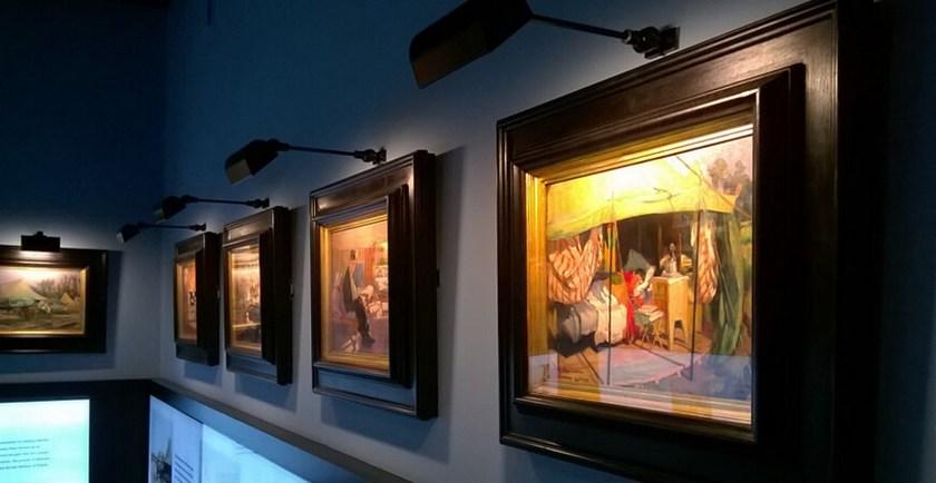 Picture wall lamp illuminating artwork inside a luxury gallery and hospitality interior.
