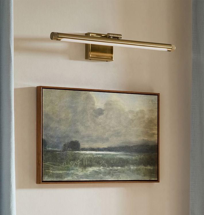 Picture wall lamp illuminating artwork inside a luxury gallery and hospitality interior.