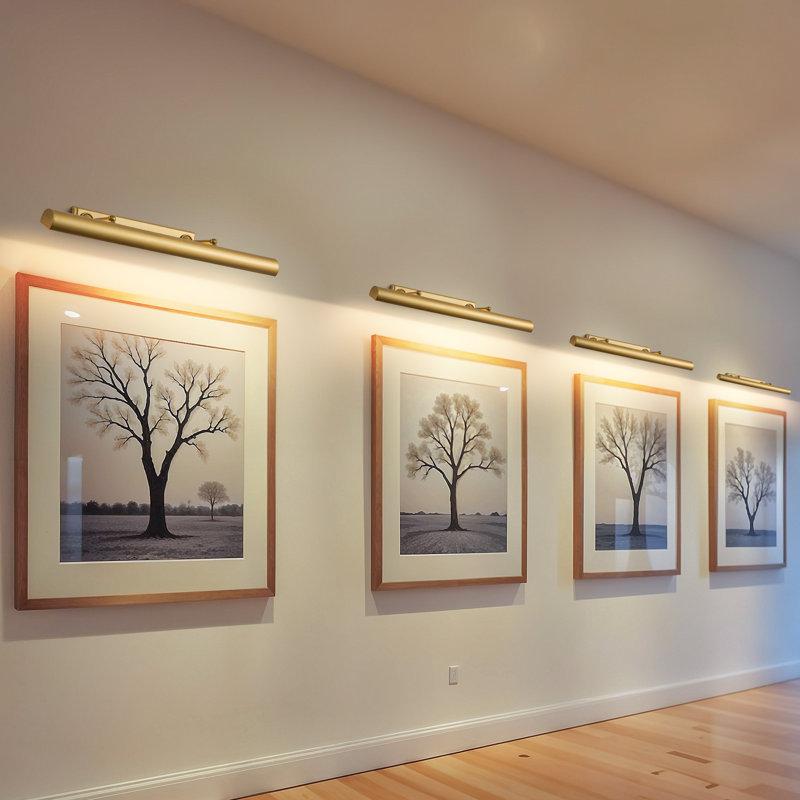 Picture wall lamp illuminating artwork inside a luxury gallery and hospitality interior.