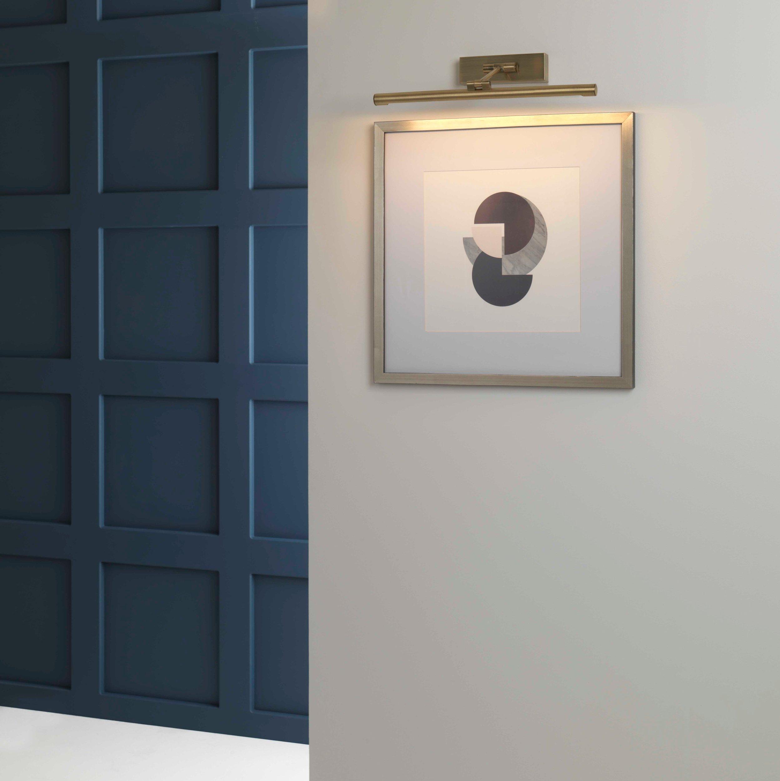 Picture wall lamp illuminating artwork inside a luxury gallery and hospitality interior.