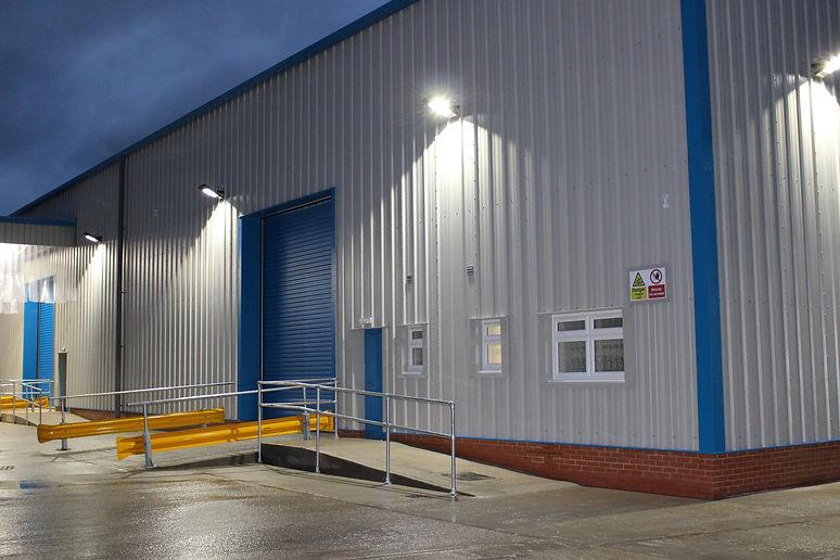 Solar LED floodlights illuminating an industrial yard and public outdoor area.