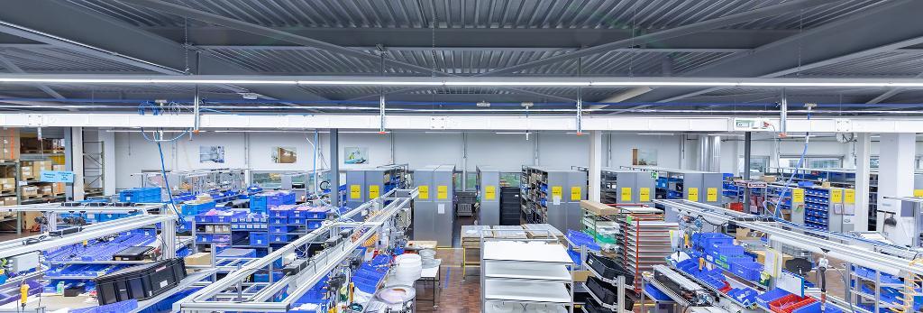 Suspended linear lights installed above a production line in a modern industrial facility.