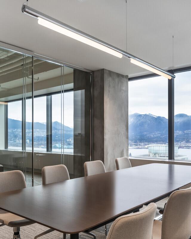 Linear pendant lighting installed in a modern office meeting room.