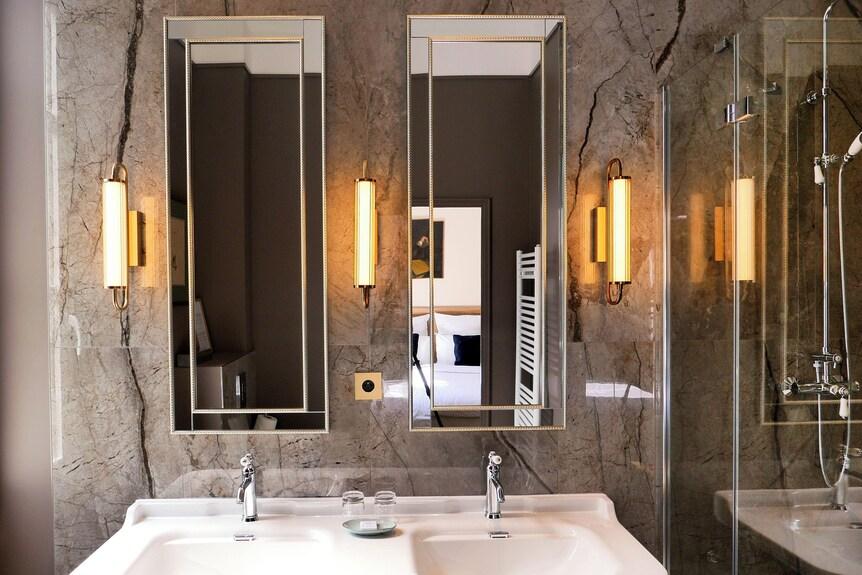 Mirror wall lamp installed beside a luxury hotel bathroom mirror providing balanced illumination.