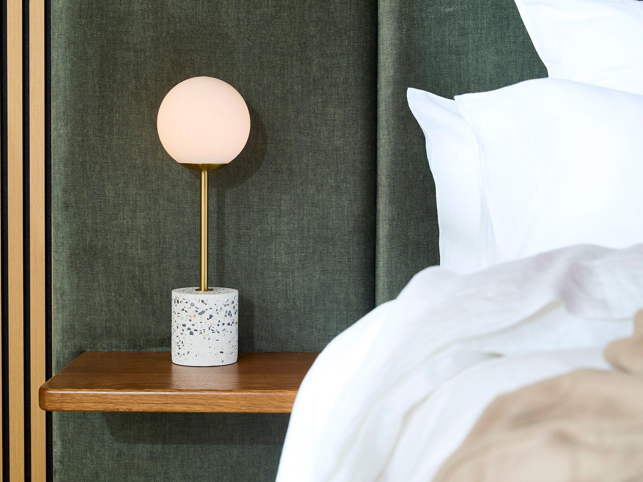 Globe table lamp placed on a luxury hotel bedside table creating soft and balanced ambient illumination.