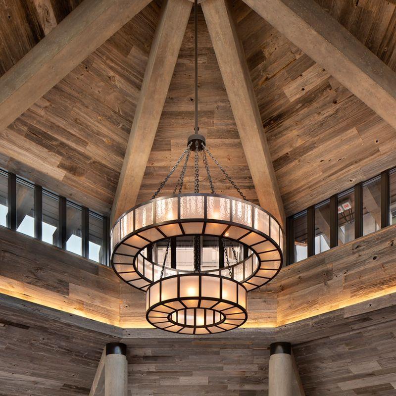 Rustic chandelier installed in a luxury mountain lodge with warm architectural interiors.