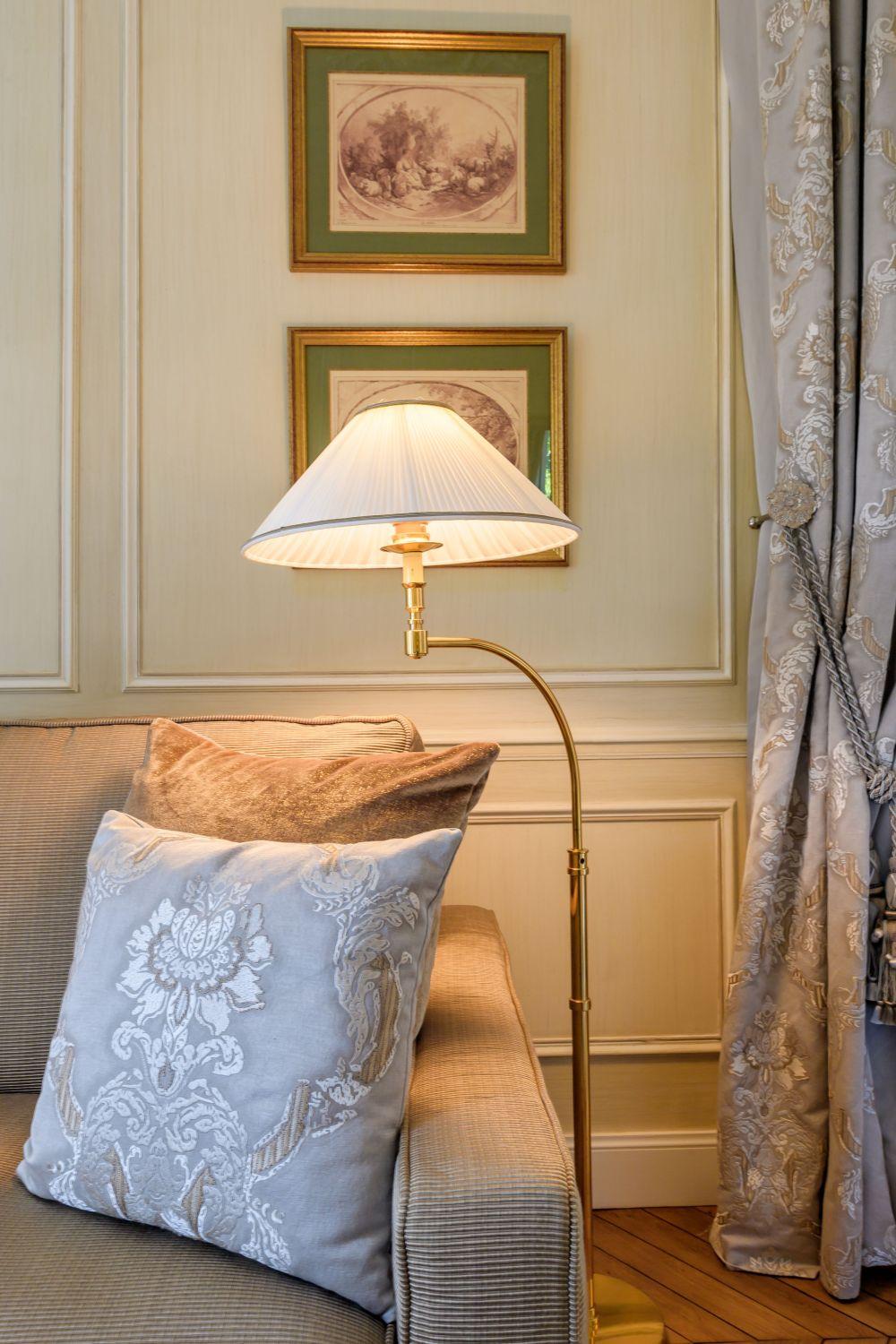 Classic floor lamp positioned beside a seating area in a luxury hotel lounge, creating warm ambient lighting and timeless sophistication.