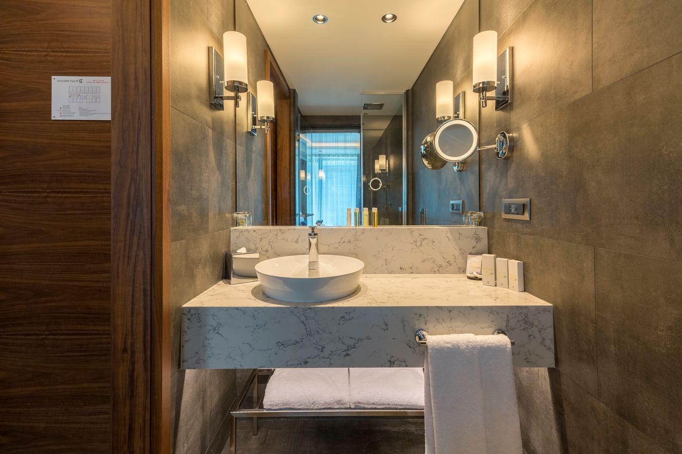 Bathroom wall lamp installed in a luxury hotel bathroom creating soft, balanced architectural lighting.