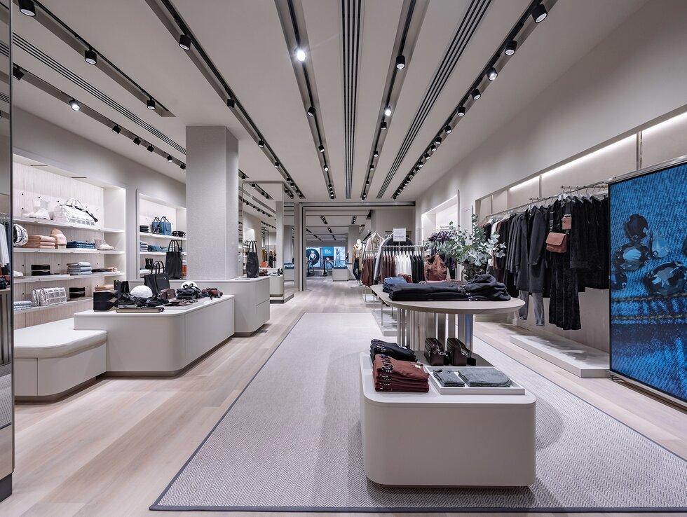 Track-mounted display lighting systems illuminating merchandise in a contemporary retail environment.