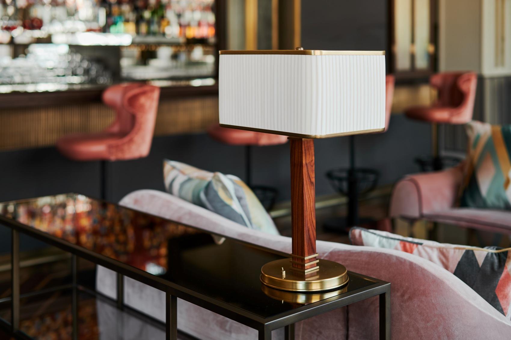 Art Deco table lamp placed in a boutique hotel lounge creating a glamorous atmosphere with warm ambient lighting.