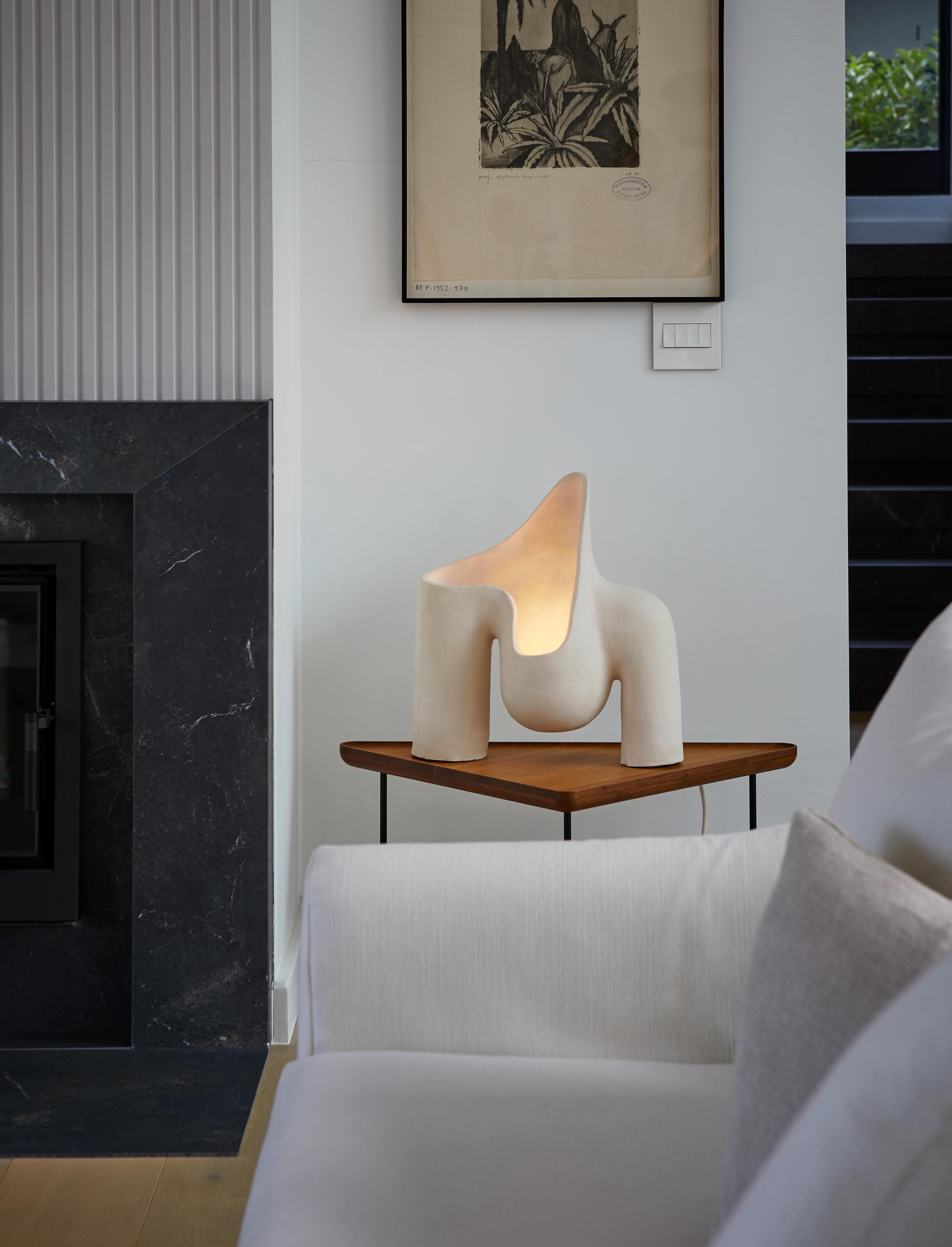 Organic table lamp placed on a wooden side table in a contemporary residential living room creating warm ambient lighting.