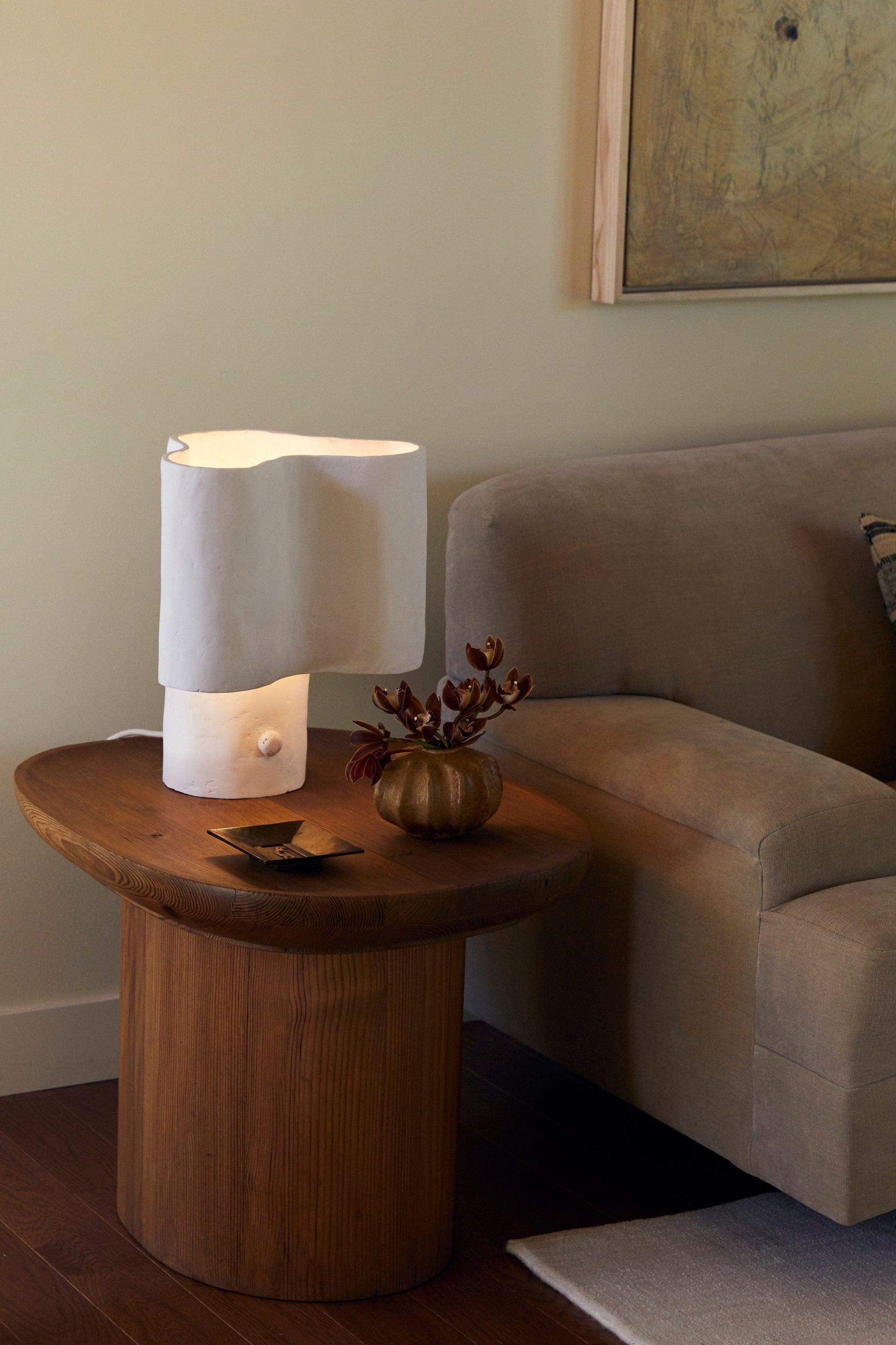 Organic table lamp placed on a wooden side table in a contemporary residential living room creating warm ambient lighting.